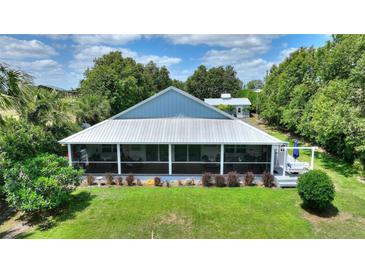 Charming screened porch overlooks the lush backyard with mature landscaping and a metal roof at 1395 S Lake Reedy Blvd, Frostproof, FL 33843