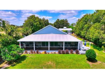 Charming home featuring a metal roof, spacious screened porch, and well-manicured lawn at 1395 S Lake Reedy Blvd, Frostproof, FL 33843