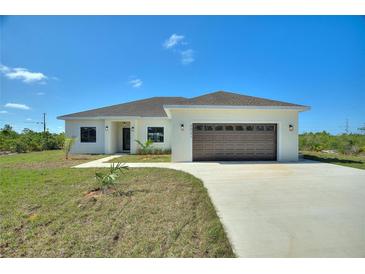 Charming single-story home featuring a two-car garage, neutral stucco, and a well-manicured lawn at 2021 Valencia Dr, Indian Lake Estates, FL 33855