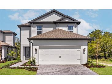Two-story home featuring a two-car garage, complemented by well-manicured landscaping, and a charming entryway at 7688 Somersworth Dr, Kissimmee, FL 34747