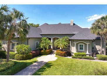 Stunning home with a manicured lawn, lush landscaping, and a grand entrance with palm trees, bushes and inviting walkway at 2660 Wyndsor Oaks Way, Winter Haven, FL 33884