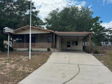 Charming single-story home with a carport, screened porch and well-maintained landscaping at 11407 Bobwhite Blvd, Leesburg, FL 34788