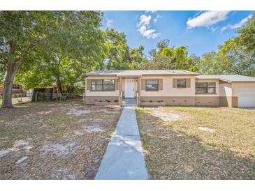 Charming single-story home with a classic design and a well-maintained yard and a long concrete walkway to the front door at 406 W Valencia St, Lakeland, FL 33805