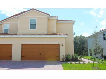 Beige two-story home featuring a two-car garage and a red tile roof at 587 Bay Leaf Dr, Poinciana, FL 34759