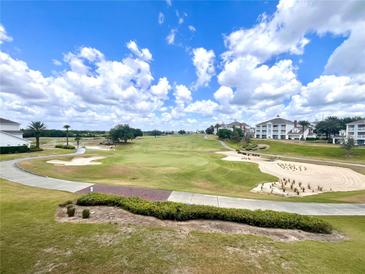 Scenic view of a lush golf course with sand traps and mature trees under a blue sky with fluffy clouds at 7673 Heritage Crossing Way # 202, Reunion, FL 34747