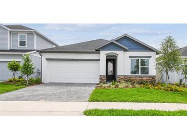 Charming single-Gathering home boasts stone accents, a well-manicured lawn, and an attached two-car garage at 5914 Bristle Oak St, Mount Dora, FL 32757