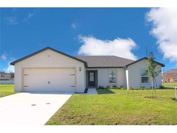 Charming single-story home with a two-car garage and well-manicured lawn at 113 Cimarron Ln, Poinciana, FL 34759