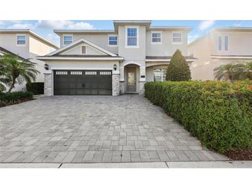 Charming two-story home featuring a paved driveway, a two-car garage, and lush landscaping at 7682 Fairfax Dr, Kissimmee, FL 34747