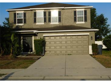 Two-story house with tan exterior, grey shutters, and a two car garage at 6954 Glenbrook Dr, Lakeland, FL 33811