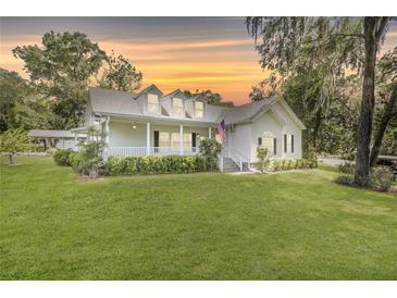 Charming two-story home with a welcoming front porch, well-maintained lawn, and a beautiful, colorful sunset at 7165 Cr 655, Bushnell, FL 33513