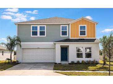 Two-story home featuring a two-car garage and a mix of blue and yellow siding at 1042 Foreshore Ln, Haines City, FL 33844