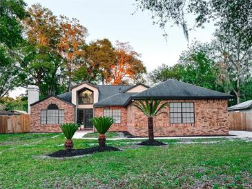 Charming brick home features a well-manicured lawn with healthy green grass and mature landscaping at 1507 Wheeler Rd, Apopka, FL 32703