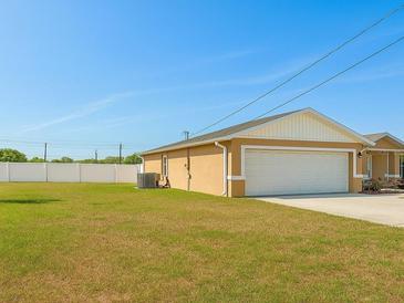View of the house's side and two car garage with a big backyard with a white fence at 1 Pecan Course Cir, Ocala, FL 34472