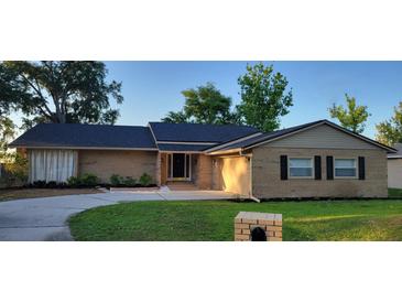 Charming brick home featuring a well-manicured lawn and a driveway leading to a welcoming entrance at 1524 New Jersey Oaks Ct, Lakeland, FL 33801