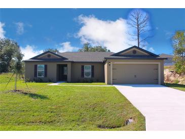 Charming single-story home featuring a manicured lawn, two-car garage and neutral-colored exterior at 414 Caribbean Ct, Poinciana, FL 34759