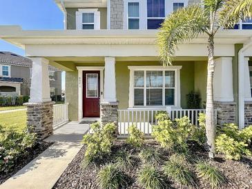 Charming home featuring a cozy front porch, a beautiful garden, and a welcoming red door at 9971 Highland Sky Aly, Orlando, FL 32832