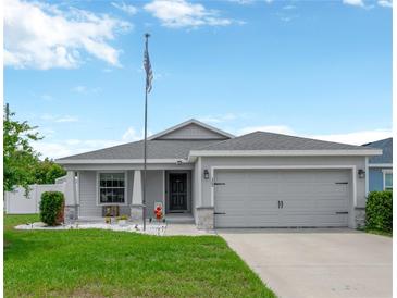 Charming single Gathering home with a well-manicured lawn, gray paint, and a two-car garage at 305 St Georges Cir, Eagle Lake, FL 33839