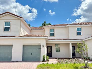 Charming two-story townhome with red tile roof, gray garage door, and well-manicured front lawn at 563 Bay Leaf Dr, Poinciana, FL 34759