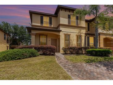 Charming two-story home with stucco exterior, dark shutters and landscaped front yard with brick pathway at 140 Napoli Dr, Davenport, FL 33897