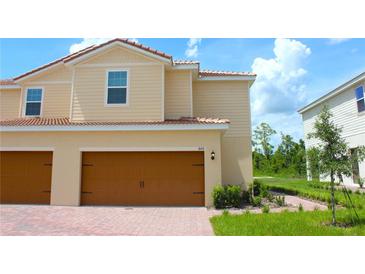 Charming two-story home with a two-car garage, well-manicured lawn, and beautiful landscaping at 600 Bay Leaf Dr, Poinciana, FL 34759