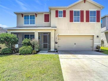Charming two-story home featuring red shutters, a well-manicured lawn, and an attached two-car garage at 159 Lazy Willow Dr, Davenport, FL 33897
