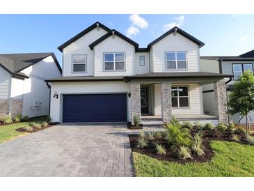 Charming two-story home with a blue garage door and stone-accented columns at 16994 Cedar Valley Cir, Clermont, FL 34711