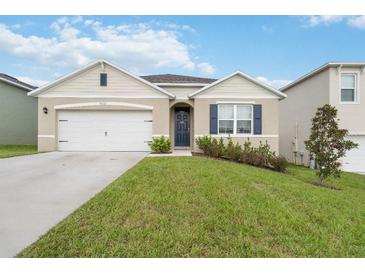 Inviting single-story home featuring a two-car garage, manicured lawn, and charming front entrance at 9532 Black Walnut Dr, Clermont, FL 34715