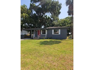 Charming single-story home featuring a cozy front porch, well-maintained lawn, and a vibrant red front door at 1727 Bonita Ave, Orlando, FL 32805
