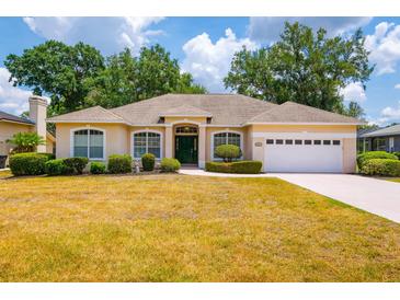 Inviting one-story home with well-manicured landscaping and a two-car garage on a sunny day at 2214 Deerbrook Dr, Lakeland, FL 33811