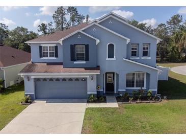 Charming blue two-story home with well-manicured lawn and attached two-car garage at 3125 Kearns Rd, Mulberry, FL 33860