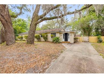 Charming single-story home with a black front door, mature trees, and a long driveway at 110 E Lauren Ct, Fern Park, FL 32730