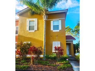 Inviting two-story home featuring a lush landscaped yard, vibrant plants, and a stately palm tree at 4720 Vero Beach Pl, Kissimmee, FL 34746