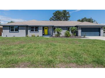 Charming gray home featuring a bright yellow front door and a well-maintained green lawn at 1416 Leighton Ave, Lakeland, FL 33803