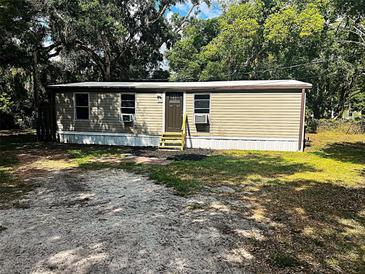 Tan home with a brown front door and well kept yard at 2434 Trenton E Rd, Lakeland, FL 33815