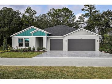 Charming single-story home featuring a two-car garage, well-manicured lawn, and modern architectural details at 6230 Sw 95Th Pl, Ocala, FL 34476