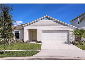 Charming single-Gathering home featuring a manicured lawn, two-car garage, and classic architectural details at 1038 Foreshore Ln, Haines City, FL 33844