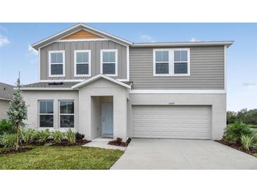 Charming two-story home with light-gray siding, a two-car garage, and a well-manicured front yard at 1205 Tidal St, Haines City, FL 33844