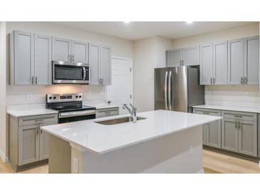Modern kitchen features stainless steel appliances, gray cabinets, and a center island with a white countertop at 3775 King Hill Dr, Haines City, FL 33844