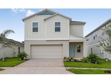 Charming two-story home showcasing a well-maintained lawn, attached garage, and a cheerful light blue front door at 4027 Gardenia Ave, Lake Hamilton, FL 33851
