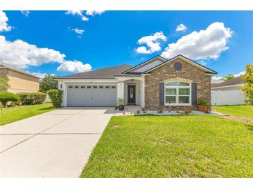 Charming single-story home with stone accents, well-manicured lawn, and attached two-car garage at 421 Sierra Mike Blvd, Lake Alfred, FL 33850