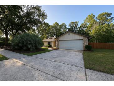 Charming single-story home featuring a well-manicured lawn, mature trees and a concrete driveway at 205 Hickory Dr, Longwood, FL 32779