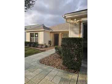 Inviting single-story home with manicured landscaping and a stone walkway to the front door at 9345 Se 171St Le Flore Ln, The Villages, FL 32162