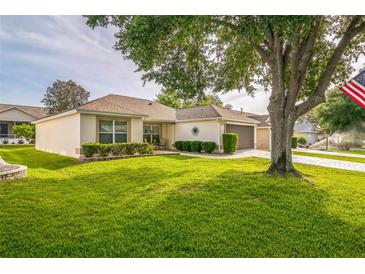Charming single-story home featuring a well-manicured lawn, mature trees, and a side-entry two-car garage at 9345 Se 171St Le Flore Ln, The Villages, FL 32162