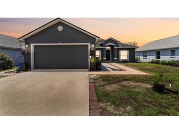Charming gray home showcasing a two-car garage, front door, manicured lawn, and beautiful brick-lined walkway at 181 Osprey Heights Dr, Winter Haven, FL 33880