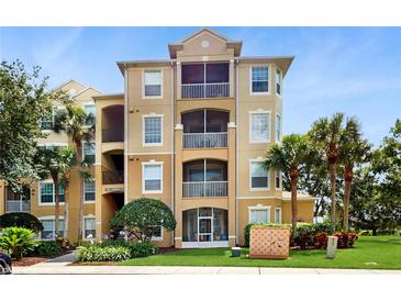 Beautiful tan condo building with mature landscaping, a well-manicured lawn, and inviting covered patios at 7654 Comrow St # 202, Kissimmee, FL 34747