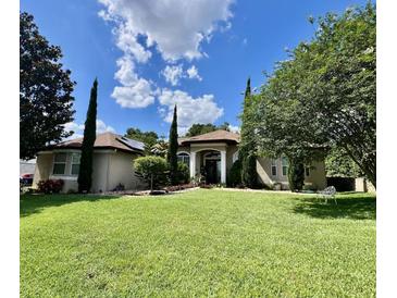 Inviting home featuring a manicured lawn, lush landscaping, and a stately entrance with white columns at 16325 Magnolia Bluff Dr, Montverde, FL 34756