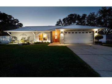 Charming single-story home with manicured lawn, stone accents, and well-lit driveway at dusk at 3610 Amber Ln, Lakeland, FL 33812