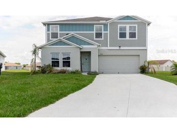 Two-story home with gray and blue siding, white trim, and a two-car garage, set on a green lawn at 1424 Axel Cir, Winter Haven, FL 33880