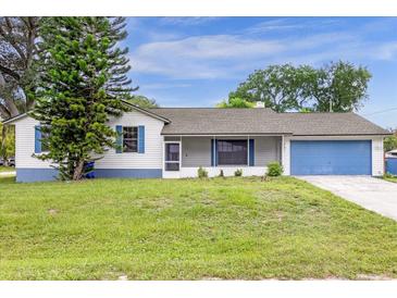 Charming single-story home with a blue garage door and shuttered windows, surrounded by a lush green lawn at 3331 Lime Tree Dr, Edgewater, FL 32141