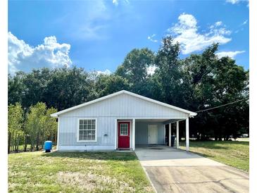 Charming single-story home with a covered carport, red front door, and well-maintained lawn at 1310 Payne St, Auburndale, FL 33823